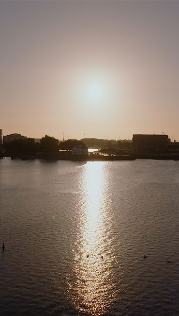 sunrise view of a waterfront, with buildings in the shadows